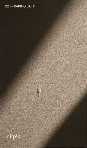 Raking light across a painted wall revealing a paint drip